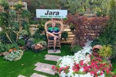 uczen-siedzi-na-wwiklinowym-krzesle-w-ogrodzie-pelnym-kwiatow